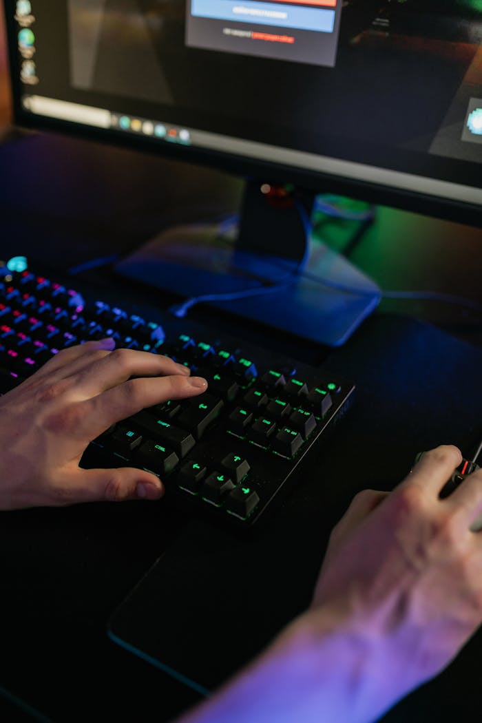Close-up of hands using a keyboard and mouse on a gaming setup with colorful lights.