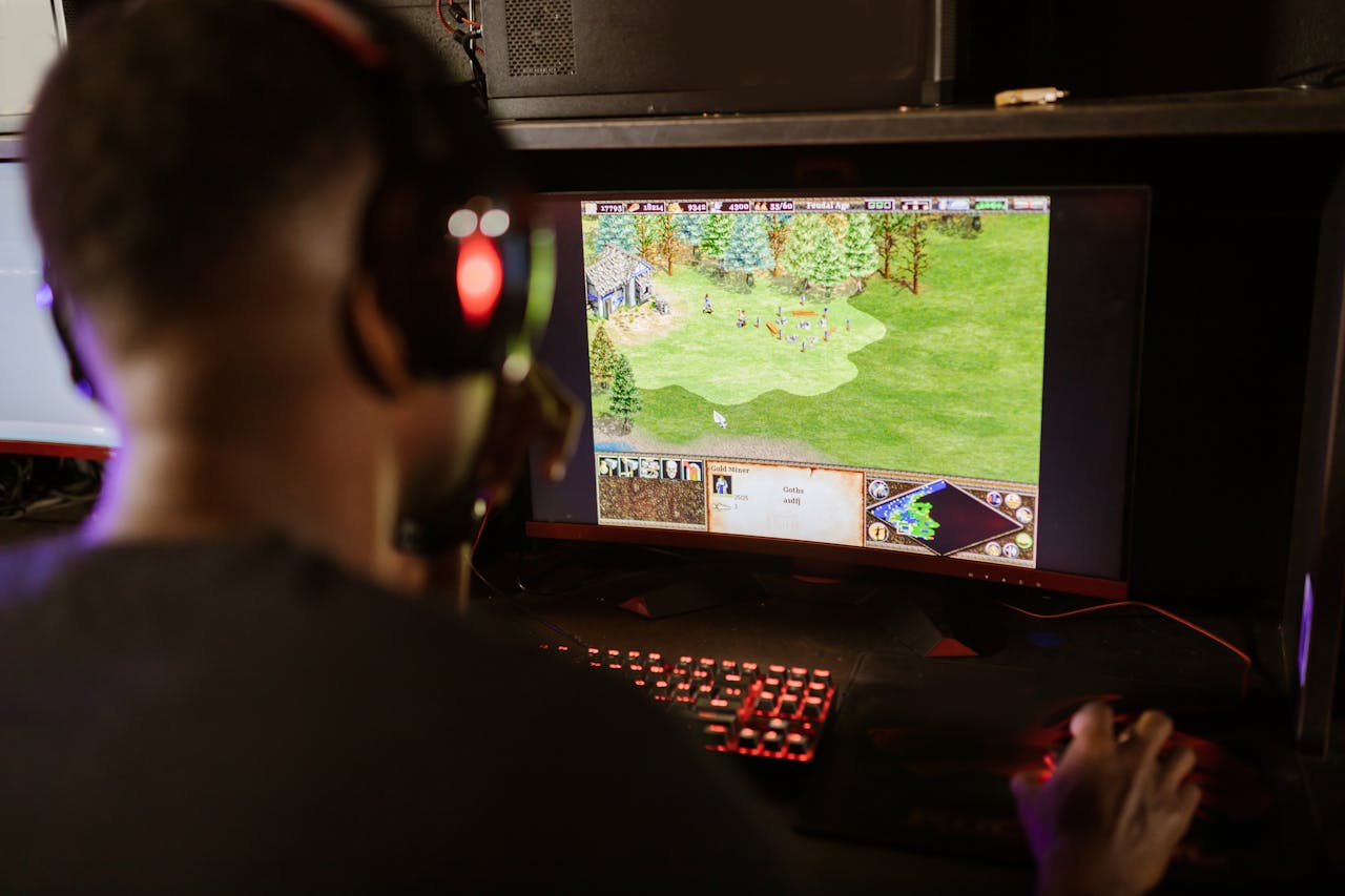 A gamer intensely playing a strategy game on a high-resolution monitor indoors.